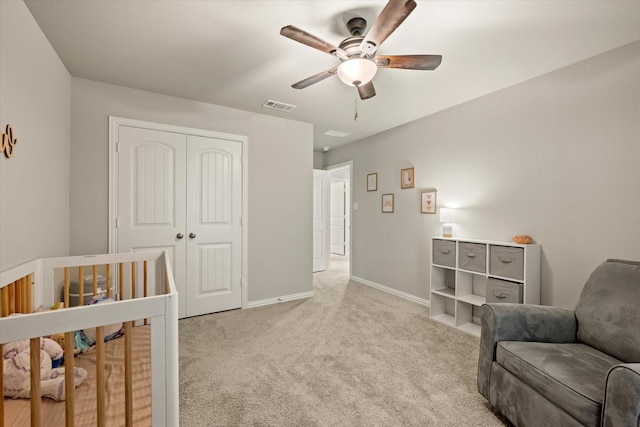 carpeted bedroom with a nursery area, a closet, and ceiling fan