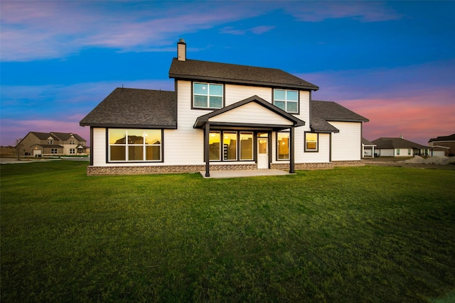 back house at dusk featuring a yard