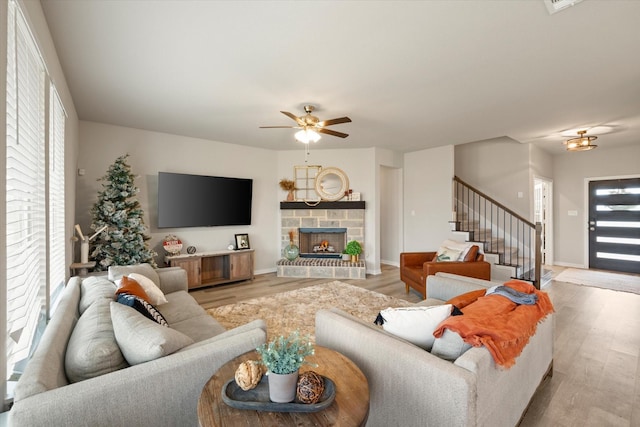 living room featuring a fireplace, light wood-type flooring, and ceiling fan