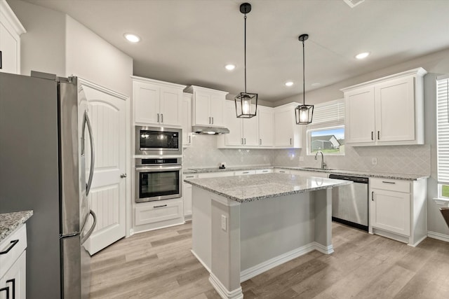 kitchen featuring light hardwood / wood-style floors, stainless steel appliances, a center island, and pendant lighting