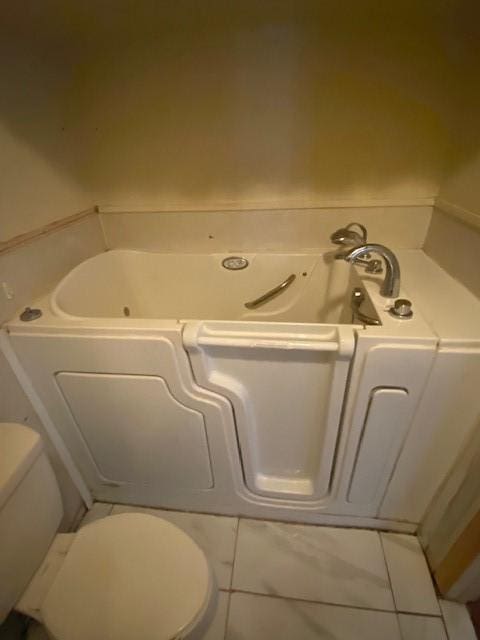 bathroom featuring tile patterned floors, a bathing tub, and toilet