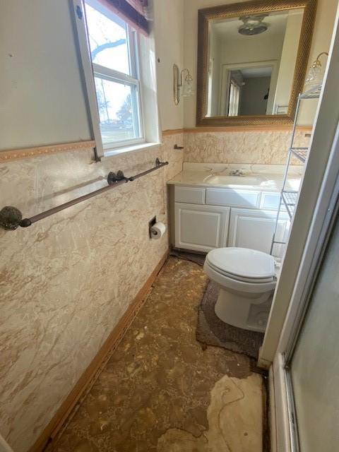 bathroom with vanity, toilet, a shower with door, and tile walls