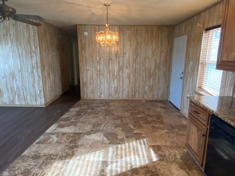 unfurnished dining area featuring ceiling fan with notable chandelier and wood walls