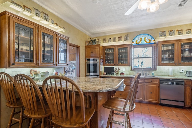 kitchen with visible vents, backsplash, a kitchen breakfast bar, stainless steel dishwasher, and a sink