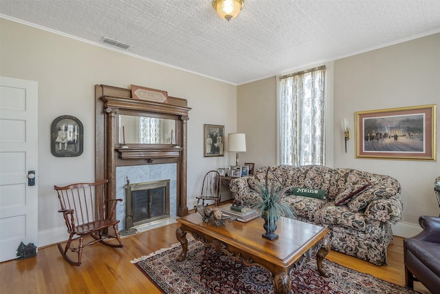 living area with wood finished floors, crown molding, and a fireplace