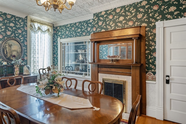 dining space featuring a chandelier, an ornate ceiling, wallpapered walls, and a fireplace