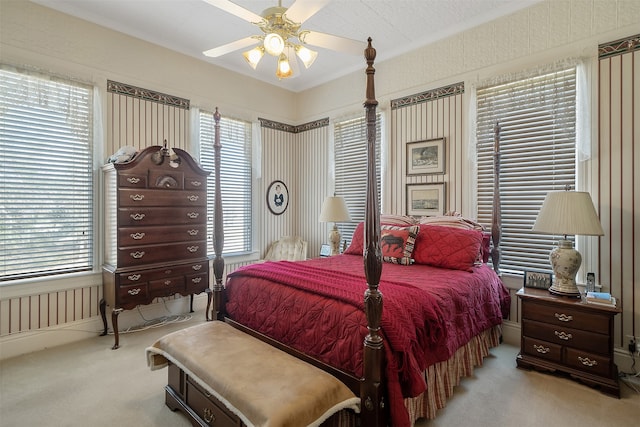 carpeted bedroom featuring multiple windows and ceiling fan