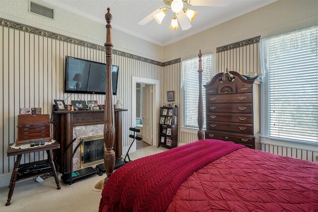 carpeted bedroom with ceiling fan, ornamental molding, and a fireplace