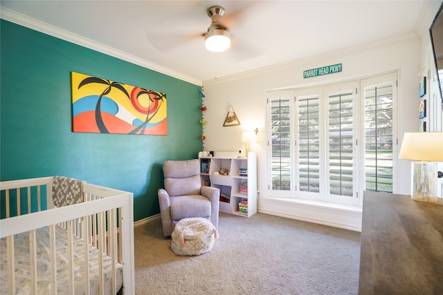 carpeted bedroom featuring a crib, ceiling fan, and ornamental molding