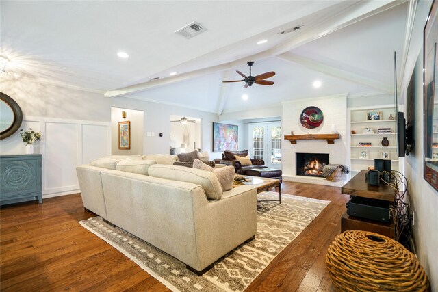 living room featuring french doors, vaulted ceiling with beams, wood-type flooring, a fireplace, and ornamental molding