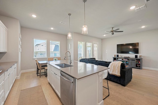 kitchen featuring stainless steel dishwasher, white cabinets, sink, and a kitchen island with sink