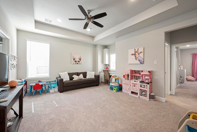 game room with carpet flooring, ceiling fan, and a raised ceiling