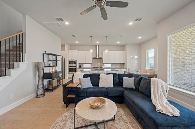 living room featuring sink, ceiling fan, and light wood-type flooring