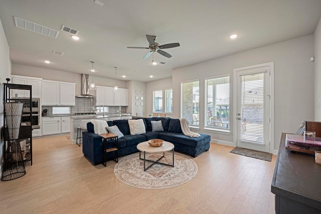 living room featuring light hardwood / wood-style flooring, ceiling fan, and sink