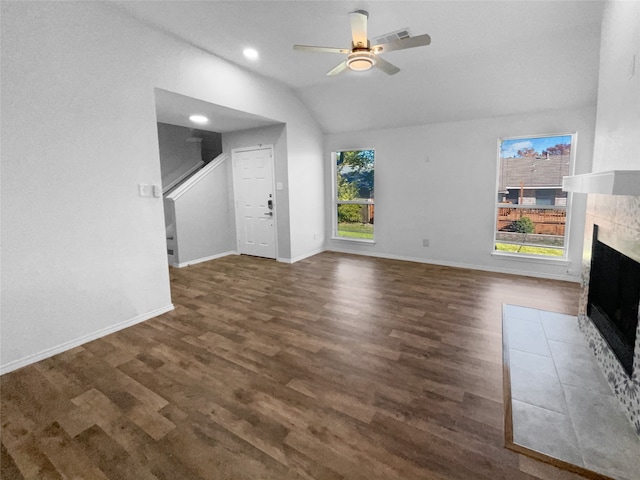 unfurnished living room with a healthy amount of sunlight, dark hardwood / wood-style flooring, lofted ceiling, and a tile fireplace