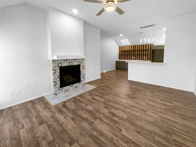 unfurnished living room with dark hardwood / wood-style floors, ceiling fan, lofted ceiling, and a tiled fireplace