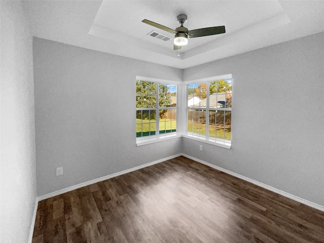 spare room with a raised ceiling, ceiling fan, and dark wood-type flooring