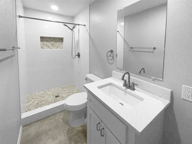 bathroom with tiled shower, tile patterned floors, vanity, and toilet