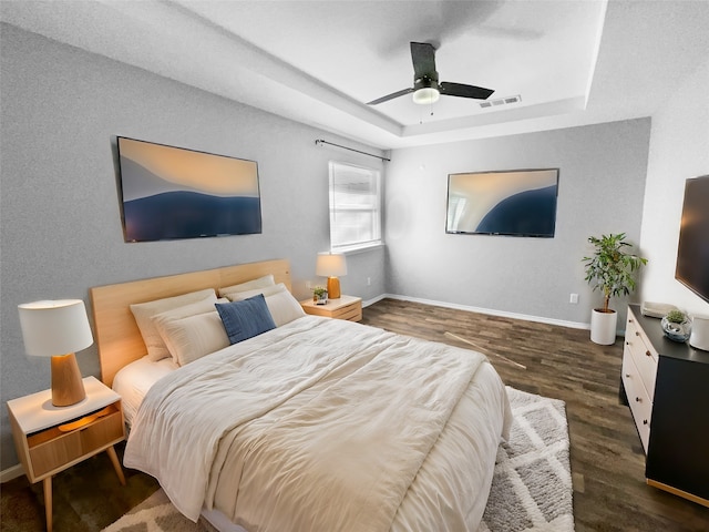 bedroom featuring a raised ceiling, ceiling fan, and dark hardwood / wood-style flooring