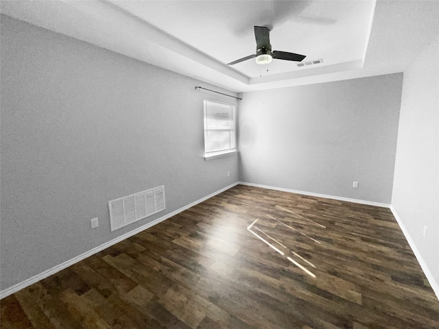 spare room featuring ceiling fan, a raised ceiling, and dark wood-type flooring