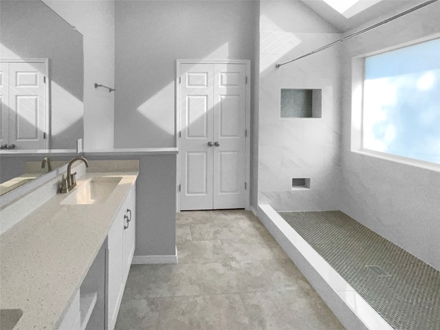 bathroom featuring a tile shower, vanity, and tile patterned floors