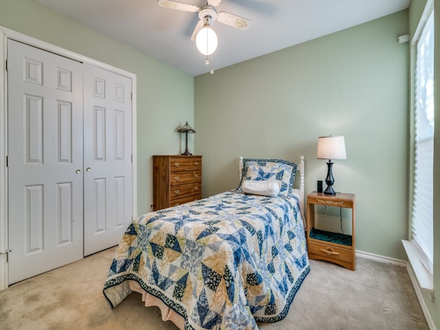 bedroom with ceiling fan, a closet, light carpet, and a textured ceiling