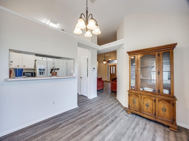 interior space with ceiling fan with notable chandelier, wood finished floors, and baseboards