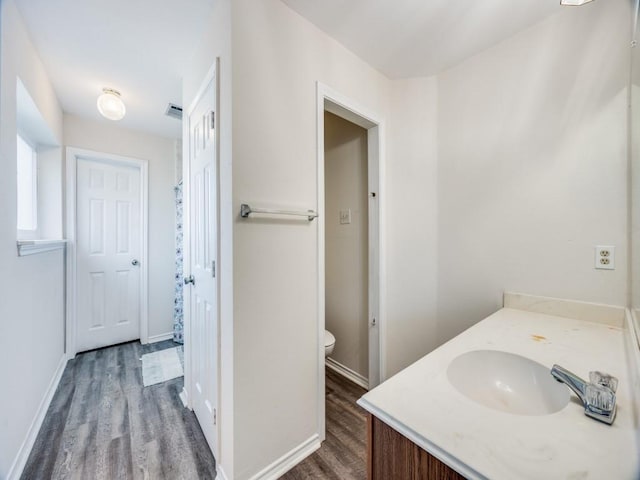 bathroom with baseboards, visible vents, toilet, wood finished floors, and vanity