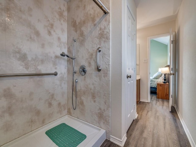 full bathroom with baseboards, tiled shower, ensuite bathroom, and wood finished floors