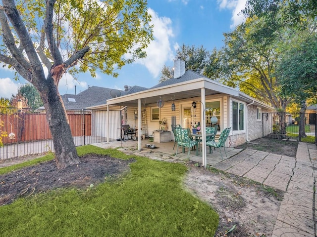 rear view of house featuring a patio area, a lawn, a chimney, and a fenced backyard