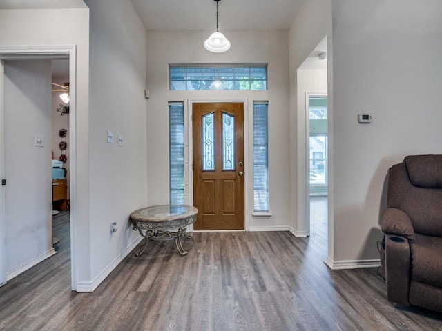 living room featuring a high ceiling, a fireplace, a ceiling fan, baseboards, and wood finished floors