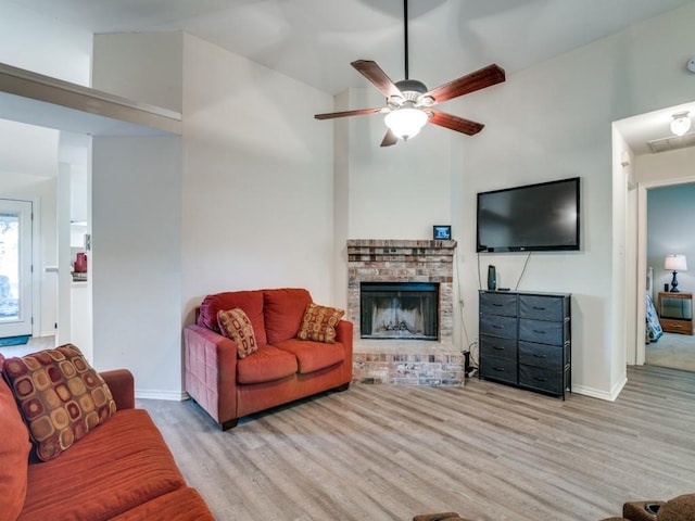 living room featuring high vaulted ceiling, a fireplace, baseboards, and wood finished floors