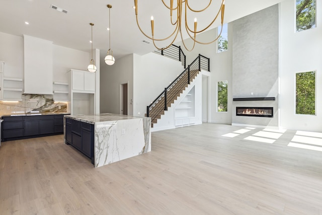 kitchen with a high ceiling, a center island, decorative light fixtures, and a large fireplace