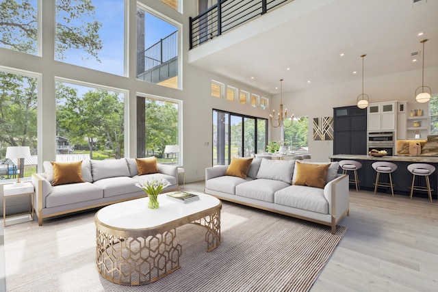 living room with light wood-type flooring, a high ceiling, and a chandelier