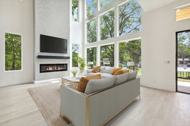 living room featuring plenty of natural light, a large fireplace, and a high ceiling