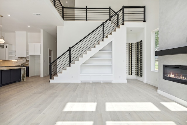 living room with light hardwood / wood-style flooring and a towering ceiling