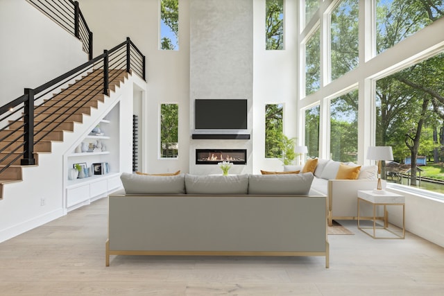 living room with light wood-type flooring, a towering ceiling, and a wealth of natural light