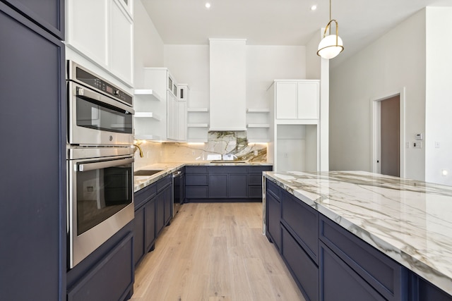 kitchen featuring white cabinetry, light stone countertops, backsplash, pendant lighting, and light wood-type flooring