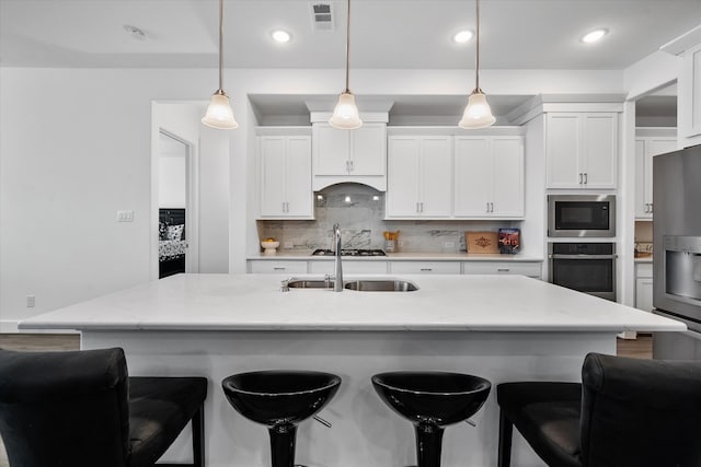 kitchen with stainless steel appliances, visible vents, backsplash, a sink, and a kitchen bar