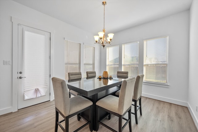 dining area with light wood finished floors, baseboards, and a notable chandelier