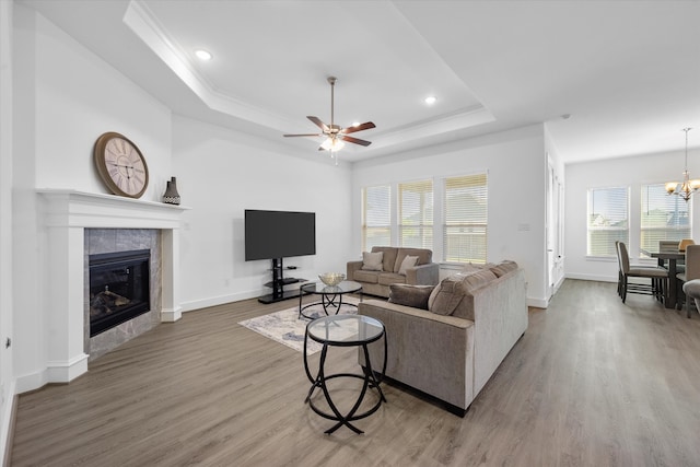 living room with a tile fireplace, a raised ceiling, baseboards, and wood finished floors