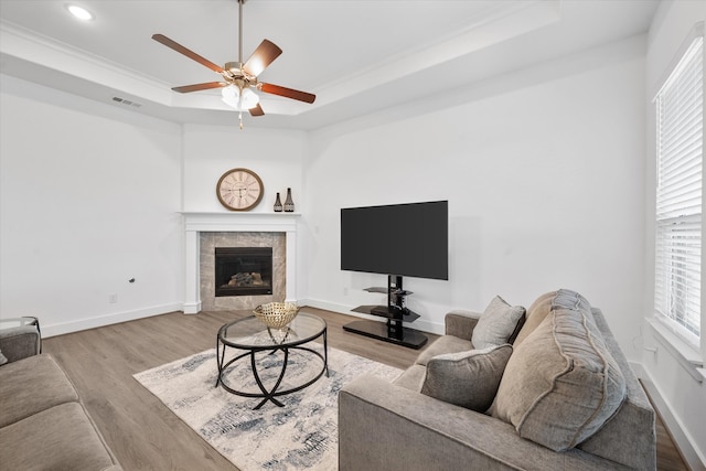 living area with baseboards, visible vents, a raised ceiling, and wood finished floors