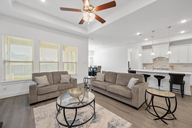 living area featuring plenty of natural light, a tray ceiling, and ornamental molding