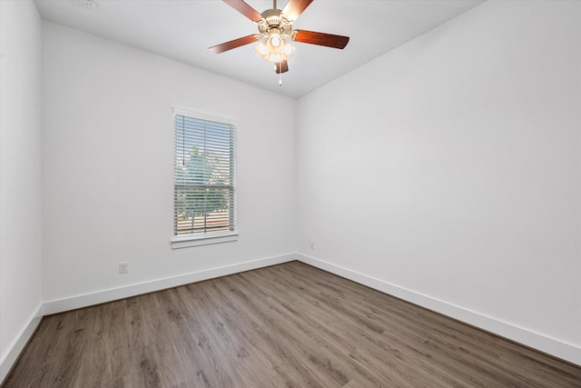 spare room featuring wood finished floors, a ceiling fan, and baseboards