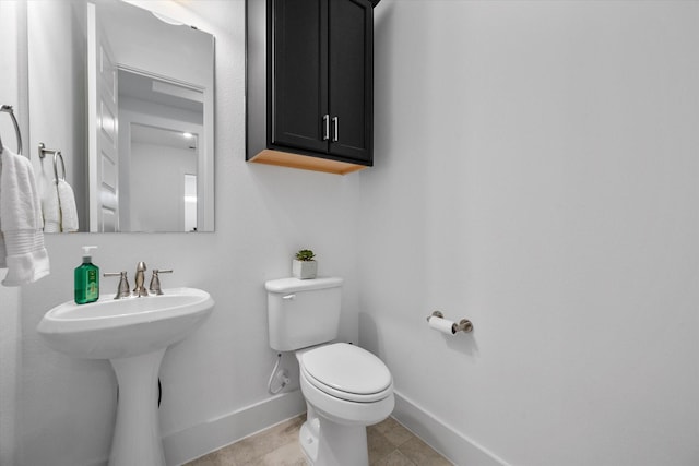 bathroom featuring toilet, baseboards, and a sink