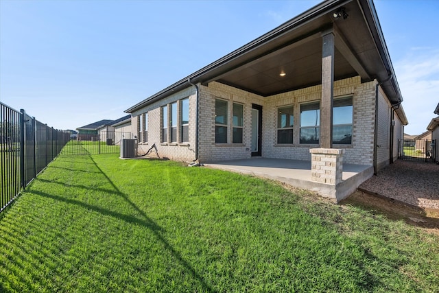 back of house featuring a yard, a patio, brick siding, and a fenced backyard