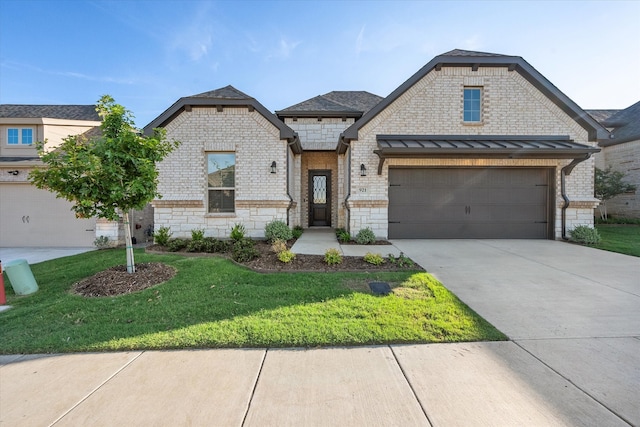 view of front of house with a garage, concrete driveway, a standing seam roof, a front lawn, and brick siding