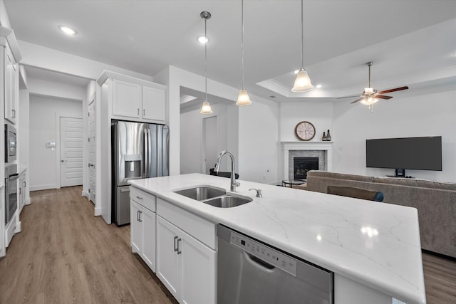 kitchen featuring a center island with sink, appliances with stainless steel finishes, light wood-style floors, open floor plan, and a sink