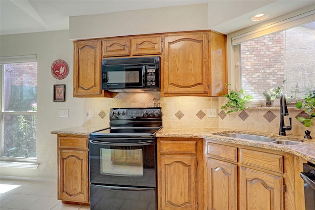 kitchen featuring tasteful backsplash, light stone countertops, sink, and black appliances