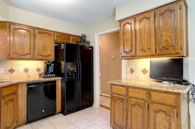 kitchen featuring tasteful backsplash, light stone counters, light tile patterned floors, and black appliances